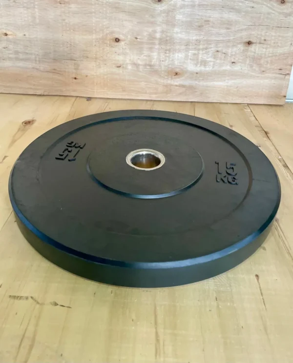 Disco bumper de 15 kg en perspectiva sobre suelo de madera.