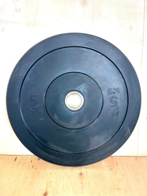 Vista de perfil de un disco bumper de 5 kg mostrando su grosor.